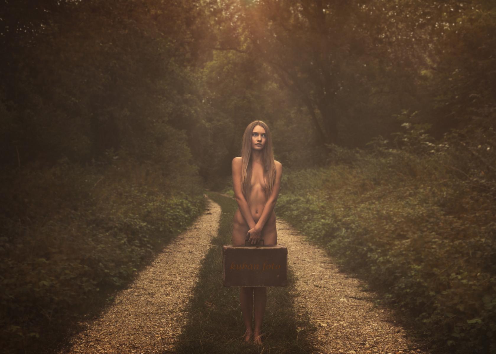 Junge Frau steht nackt auf einem Waldweg